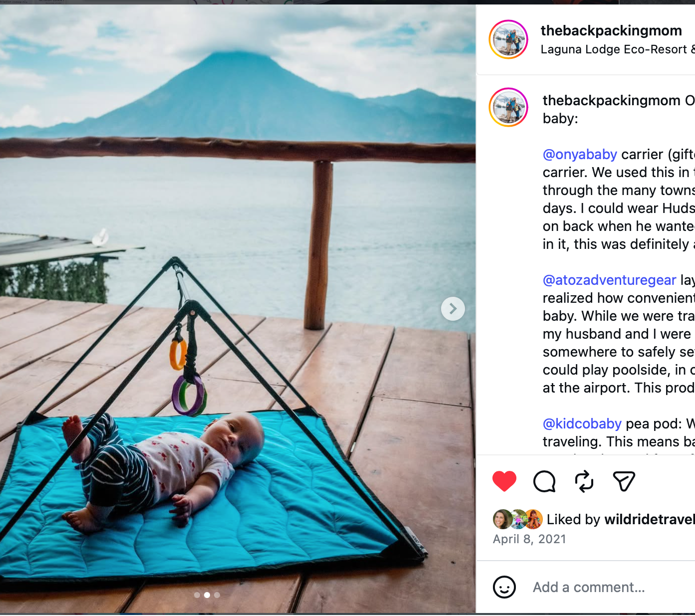 Baby lying on a blue play mat surrounded by scenic mountains and water.